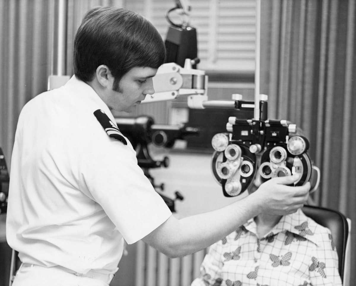 Optometrist using a phoropter to test a patient's vision during an eye exam